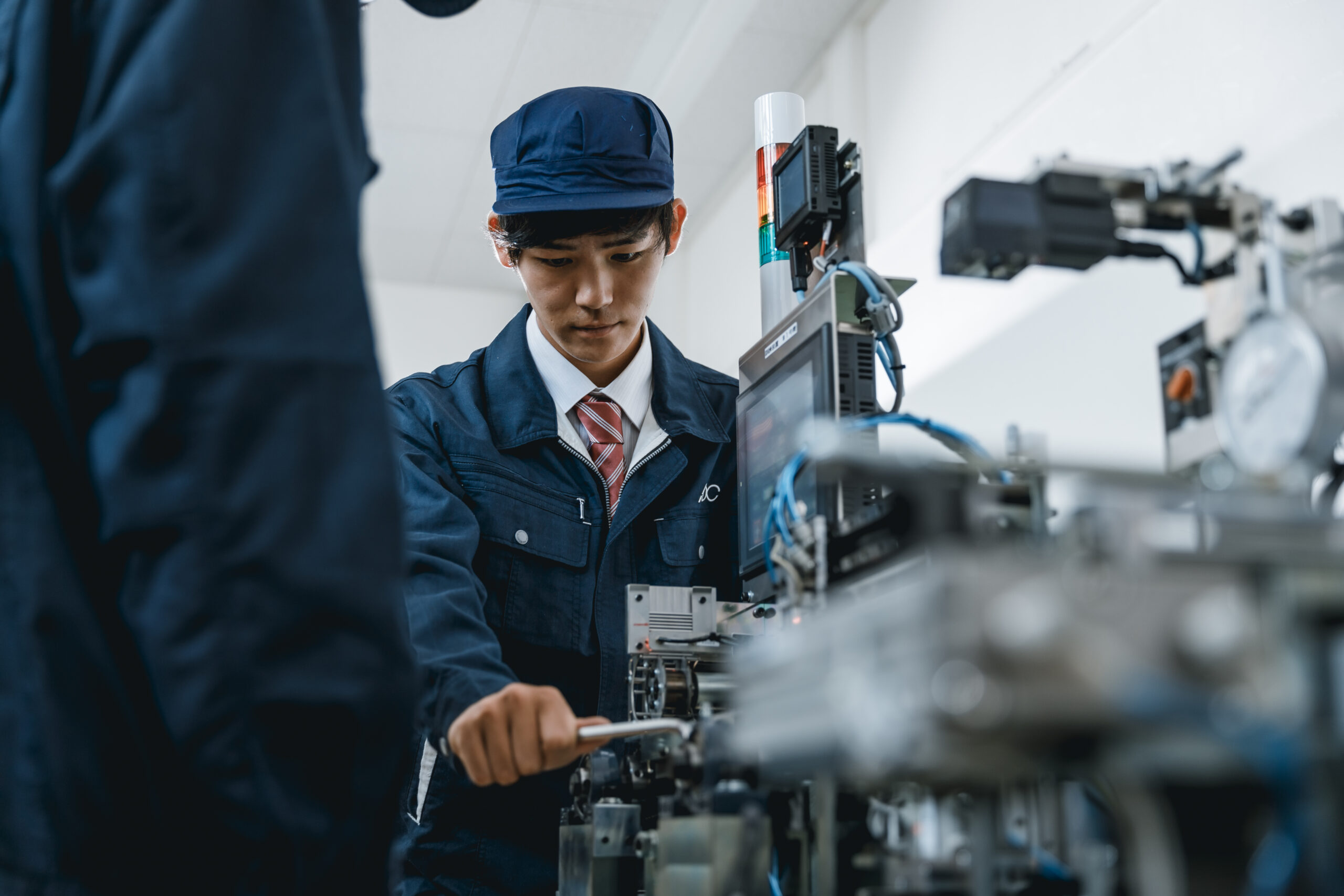 作業服を着て工場の機械を操作するスタッフの様子